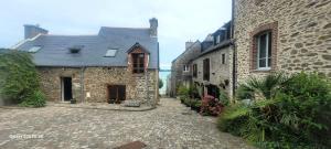 a stone house with a cobblestone street next to a building at Rêve et Rance in La Richardais