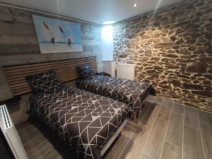 a bedroom with two beds and a stone wall at Rêve et Rance in La Richardais