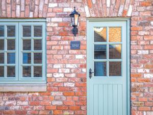 a brick building with a blue door and two windows at Peartree Cottage - Uk45496 in Great Budworth