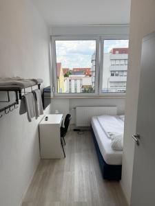 シュトゥットガルトにあるNujen- Hotel und Apartment Stuttgart Zuffenhausenのベッドと窓のある小さな部屋
