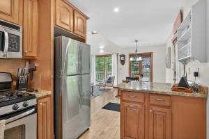 a kitchen with wooden cabinets and a stainless steel refrigerator at VT Lake house minutes from Okemo in Ludlow