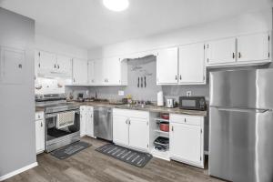a kitchen with white cabinets and a stainless steel refrigerator at Modern 3BR 2 bathroom Near High Point University & Market Sleeps 6 in High Point