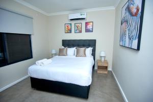 ルサカにあるEstate Apartmentsの大きなベッドと薄型テレビのある寝室