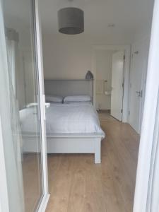 une chambre avec un lit blanc et un miroir dans l'établissement Knightstown Cottage, à Île de Valentia