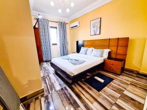 a bedroom with a bed with a wooden headboard at Belmann Bonapriso in Douala