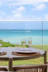 two wine glasses sitting on a table with a view of the ocean at SEA NOVA Friar's Bay Beachfront Properties in Saint Martin