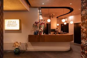a lobby with a counter with flowers on the wall at Boutique Hotel de Statie in Valkenswaard