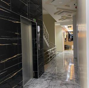 a hallway in a building with black tile walls at Ögel Apart Otel in Sarıkamıs