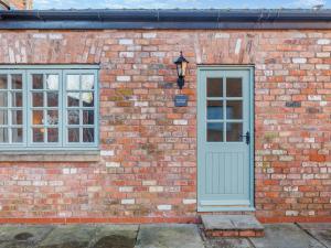 a brick building with a blue door and two windows at Rose Cottage - Uk45497 in Great Budworth