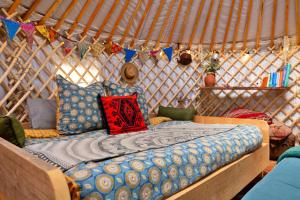 ein Bett in einer Jurte mit Kissen und Fahnen in der Unterkunft Finest Retreats - Pandy Mongolian Yurt in Penmaen Pool
