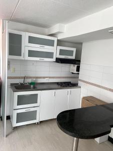 a kitchen with white cabinets and a black table at casas bosque apartaestudio in Bogotá