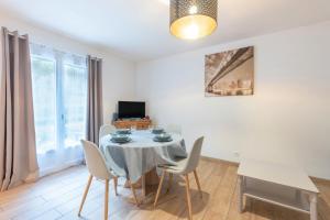 une salle à manger avec une table, des chaises et une télévision dans l'établissement Chalets De L’arriutort - Laruns, à Laruns