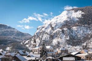 une ville en face d'une montagne enneigée dans l'établissement Chalets De L’arriutort - Laruns, à Laruns