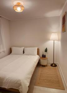 een slaapkamer met een wit bed en een lamp bij Stay comma in Seoul +9 foto's