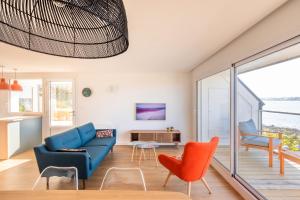 ein Wohnzimmer mit einem blauen Sofa und orangefarbenen Stühlen in der Unterkunft Logement exceptionnel, sur plage in Trélévern