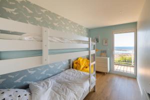 Schlafzimmer mit Etagenbetten und Meerblick in der Unterkunft Logement exceptionnel, sur plage in Trélévern