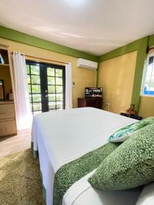 a bedroom with a large white bed and a window at Cinnamon Cottage - Peaceful retreat in nature in Soufrière