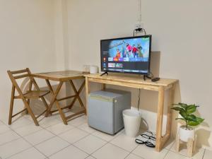 a desk with a television and a table with a computer at บ้านบี เซอร์วิส อพาร์ตเมนต์ in Si Racha