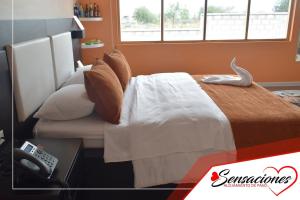 a hotel room with a bed with a phone at Motel Sensaciones in Latacunga