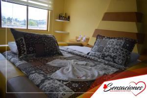 a bed with pillows and a blanket on it at Motel Sensaciones in Latacunga +6 photos