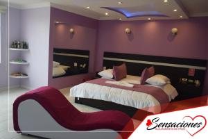 a purple bedroom with a bed and a red chair at Motel Sensaciones in Latacunga