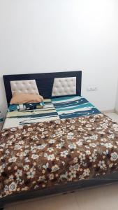 a bed with a brown bedspread with flowers on it at Elite Home Stay in Raipur +8 photos