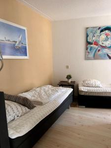 ユリアーナドルプにあるDe Duinroosのベッドが2つあり、壁に絵が飾られた寝室