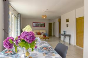 een eettafel met paarse bloemen in een vaas bij Les hortensias in Grâces