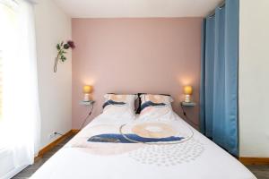 een slaapkamer met een wit bed met 2 kussens bij Les hortensias in Grâces