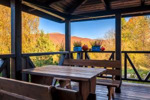 a wooden table and chairs on a porch with a view at Bieszczadzki Domek z widokiem na połoniny in Wetlina