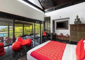 a bedroom with a bed and red chairs and a television at Villa Yin-Noi, Private Oceanfront Villa, Kamala Beach in Kamala Beach