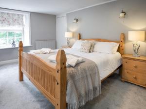 a bedroom with a large wooden bed and a window at Hudson Cottage - Uk38152 in Newton