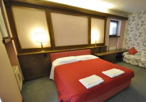 a bedroom with a red bed with two towels on it at Hotel Ristorante La Lepre Bianca in Gallio