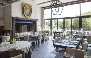 um restaurante com mesas e cadeiras e uma lareira em Logis La Ferme Du Vert em Wierre-Effroy