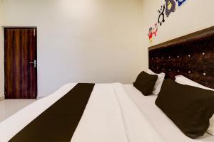 a bedroom with a large white bed with black pillows at Hotel O KAILASHA INN in Hasanganj +19 photos