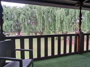 a porch with two chairs and a view of trees at The Nugget Guest Lodge in Kempton Park +4 photos