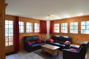 a living room with black leather furniture and windows at Platane B 04 in Grimentz