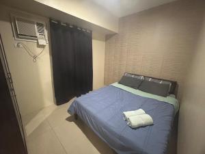 een slaapkamer met een bed met blauwe lakens en een raam bij 2Bedroom 2Bathroom AvidaRialaTowers with Pool Netflix in Cebu City +48 foto's