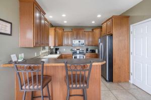 a kitchen with wooden cabinets and a island with two bar stools at The Greenview Manor with Lake Views in Kimberling City +19 photos