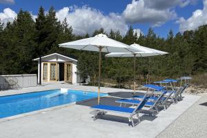 a group of chairs and umbrellas next to a swimming pool at Villa Vitviken Sleeps 4 with Pool in Slite