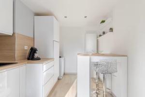 a kitchen with white cabinets and a stool in it at Un des sens, vue port, Sauna et Spa in Le Tréport