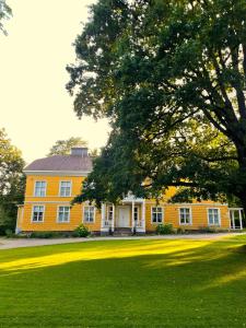 a large yellow house with a tree in front of it at Tehtaan Hotelli in Karkkila