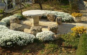 a stone bench in a garden with white flowers at Lovely Apartment In Omis With Wifi in Tice +13 photos