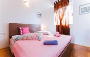 a bedroom with a pink bed with two pillows on it at Lovely Apartment In Omis With Wifi in Tice