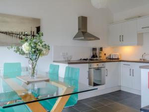 a kitchen with a glass table and blue chairs at Primrose in Shepton Mallet