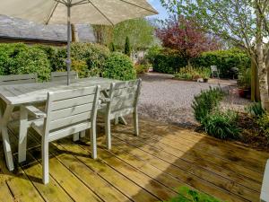 a wooden deck with a table and chairs and an umbrella at Primrose in Shepton Mallet