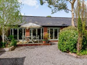 a brick house with a table and an umbrella at Primrose in Shepton Mallet