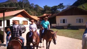 a group of people riding horses in front of a house at Pousada Fazenda Pedra Riscada in Lumiar