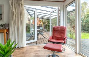 a screened in porch with a red chair and a deck at 2 Bedroom Awesome Home In Erm in Erm