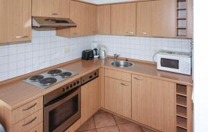 een keuken met houten kasten, een wastafel en een magnetron bij Gorgeous Home In Röbel With Lake View in Marienfelde